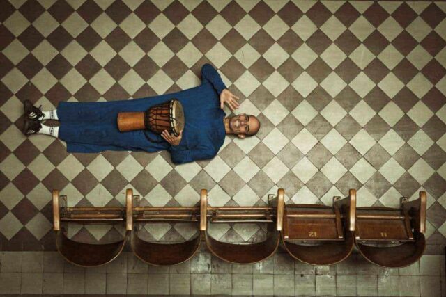 Wesoły mężczyzna bębnem w ręce leży na posadzce