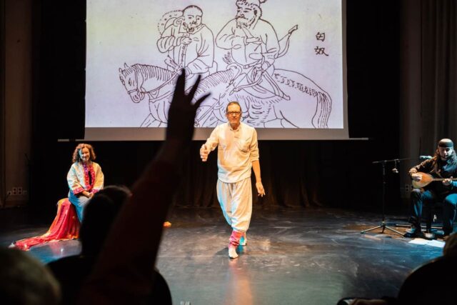 Trzy osoby na scenie, grafika w tle