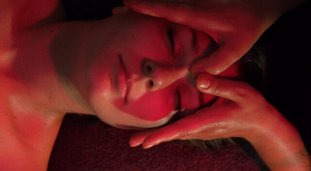 Kobieta w czerwonym świetle ma masowaną twarz