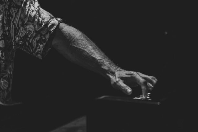 Dłoń mężczyzny naciskająca klawisze fortepianu.