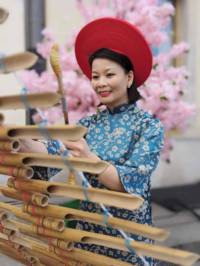 Wietnamka gra na instrumencie, w tle kwiaty