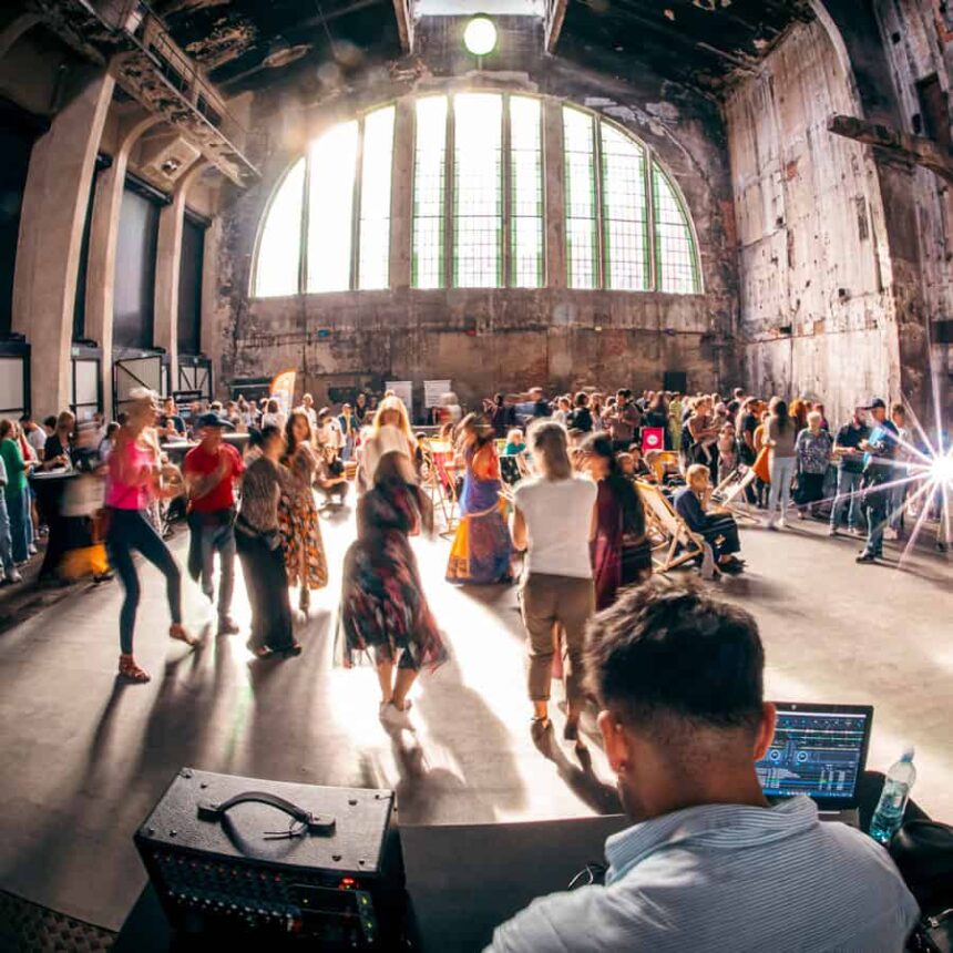 Ludzie tańczący w industrialnej przestrzeni, DJ na pierwszym planie