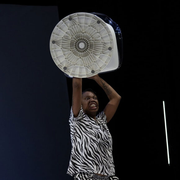 czarnoskóra kobieta w czarno-białym stroju z wentylatorem uniesionym w górę