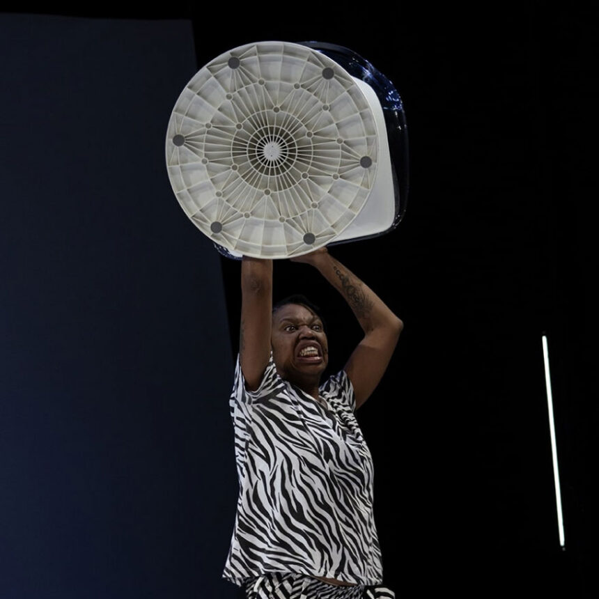 czarnoskóra kobieta w czarno-białym stroju z wentylatorem uniesionym w górę