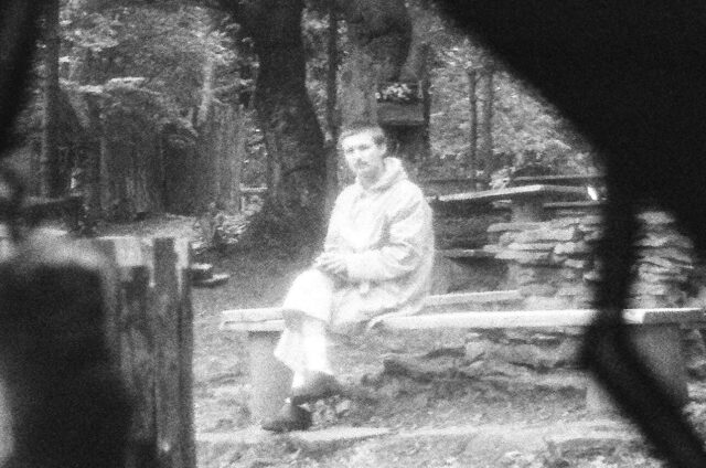 Czarno białe zdjęcie siedzącego w plenerze mężczyzny