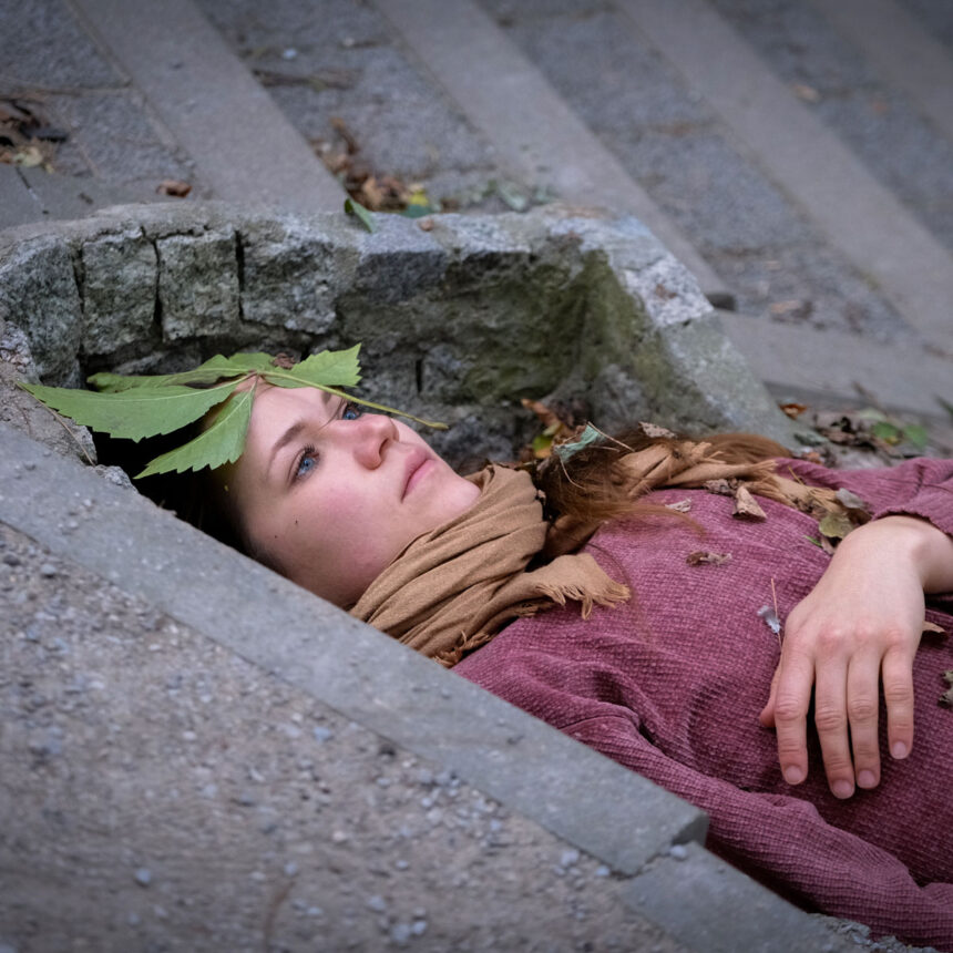 Kobieta z liściem na głowie leży na betonie