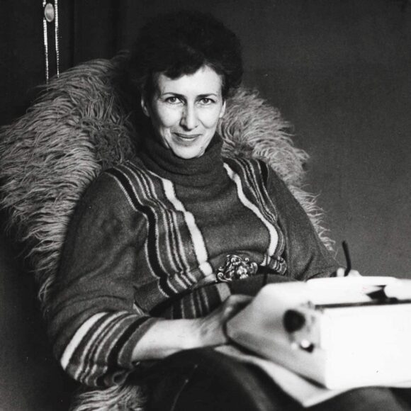 Kobieta Joanna Kulmowa siedząca w fotelu z maszyną do pisania na kolanach