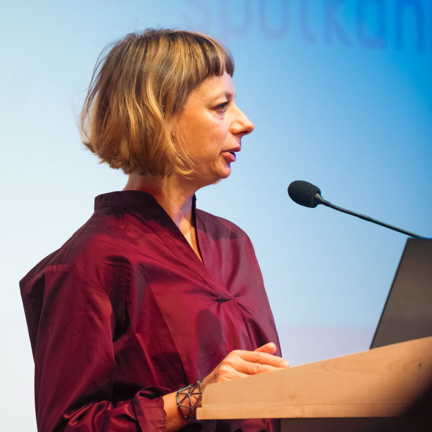 Kobieta w bordowej bluzce przy mikrofonie