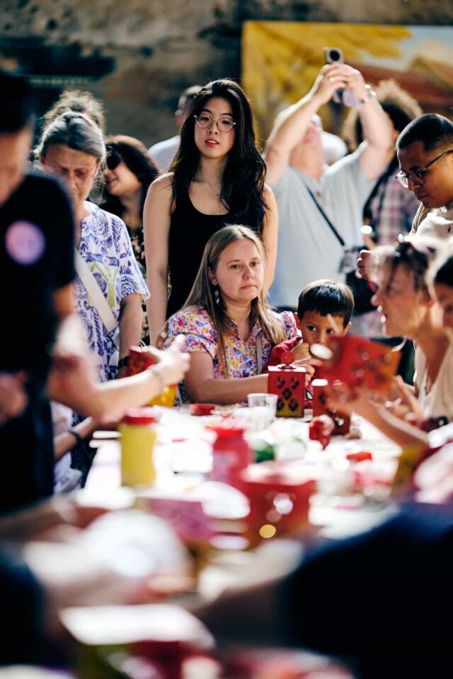 Grupa osób przy stole na którym odbywają się warsztaty plastyczne