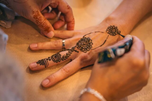 Zbliżenie na dłonie w trakcie wykonywania tradycyjnej henny (tatuażu)
