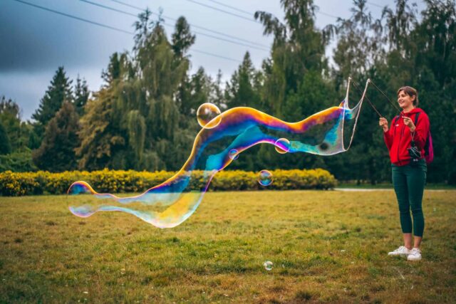 Kobieta puszczająca ogromną podłużną bańkę