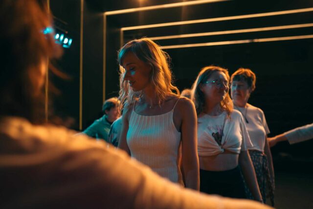 Grupa kobiet z zamkniętymi oczami w ciemnym pomieszczeniu