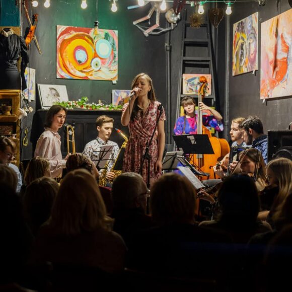 Zespół z wokalistką gra przed publicznością przed publicznością we wnętrzu