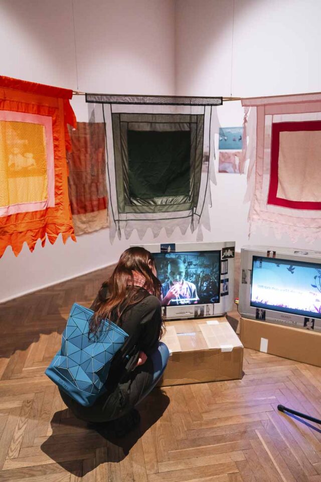 Kobieta w środku instalacji z tkanin i odbiorników tv