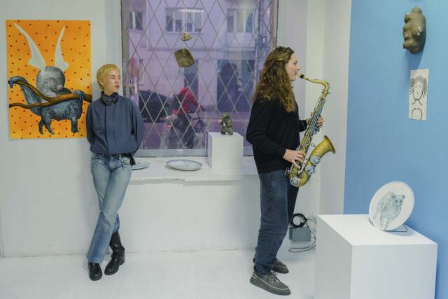 Mężczyzna grający na saksofonie i kobieta we wnetrzu galerii