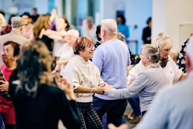 seniorki tańczą w parze w tłumie innych ludzi