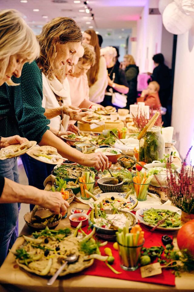 Ludzie nakładają jedzenie z bogato zastawionego stołu