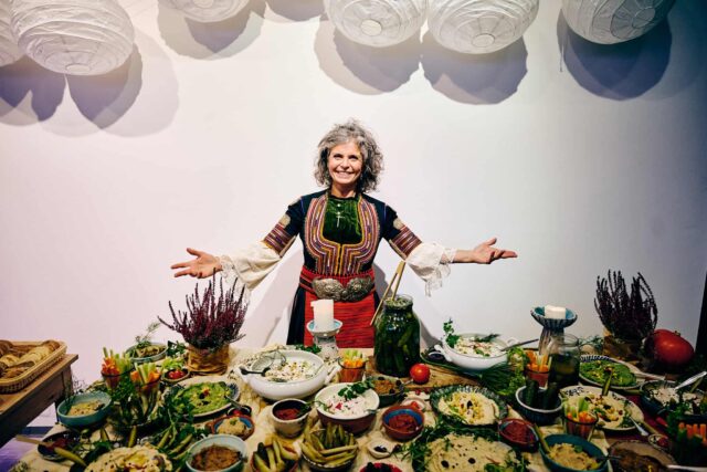 Kobieta z otwartymi rękami przy stole pełnym jedzenia