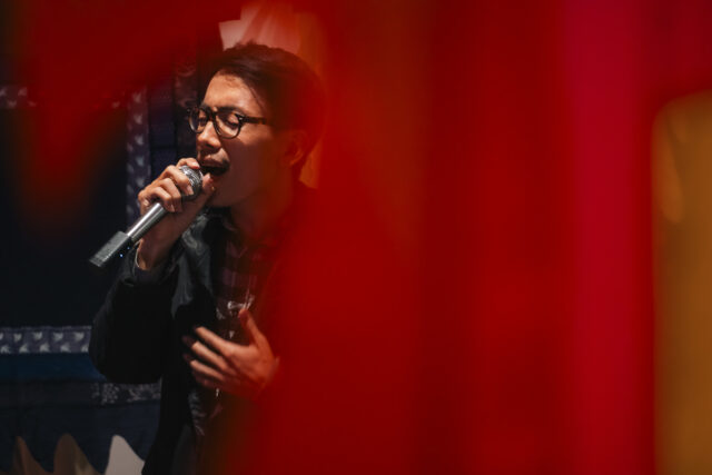 Mężczyzna Wietnamczyk śpiewa na pierwszym planie czerwona zasłona