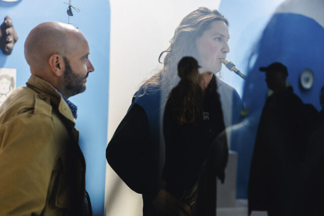 Mężczyzna gra na saksofonie, inni ludzie w tle i odbiciach