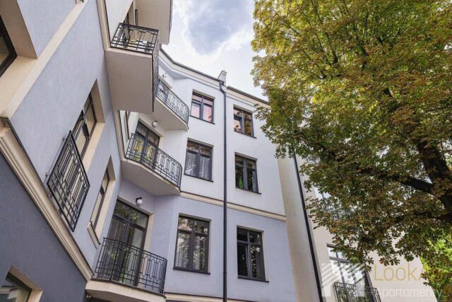 Widok na odnowioną kamienicę, drzewa z prawej strony