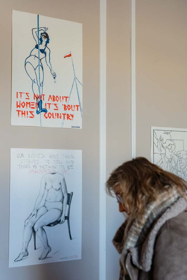 kobieta ogladajaca grafiki na scianie