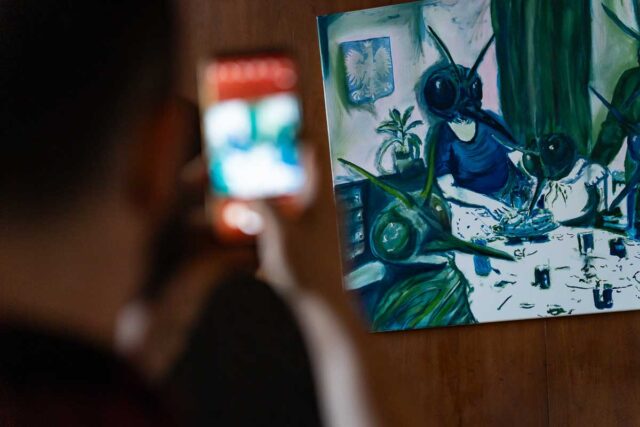 osoba robiąca zdjęcie na pierwszym planie, na drugim obraz malarski