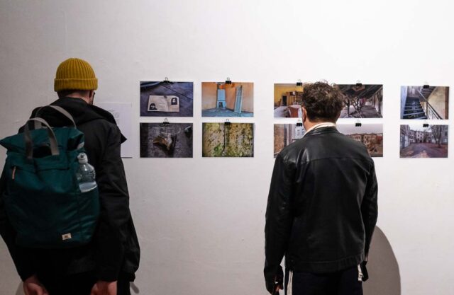 dwie osoby tyłem oglądają zdjecia na białej ścianie