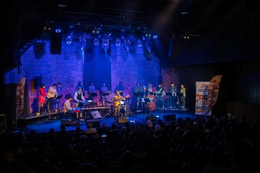 zespol 19 osoby na scenie w niebieskim świetle