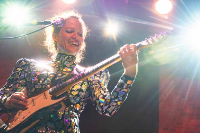 Usmiechnięta kobieta grająca na gitarze elektrycznej