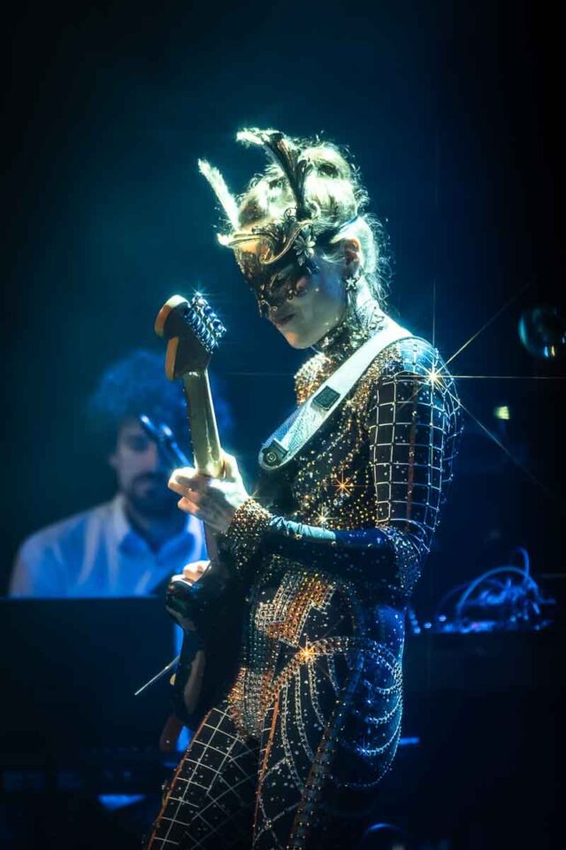 Kobieta w masce na oczach gra na gitarze