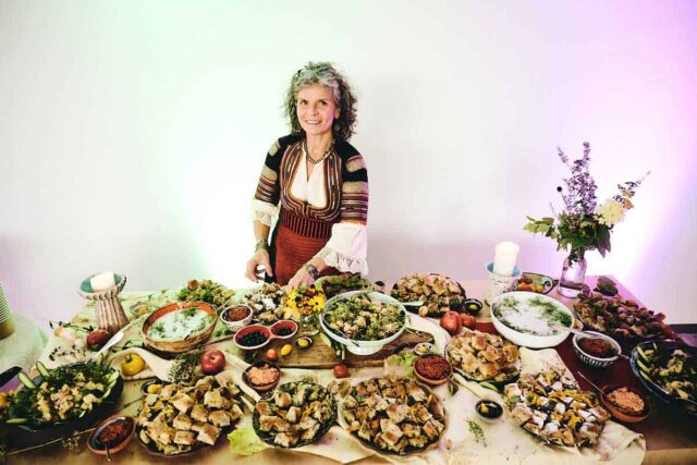 Kobieta w tradycyjnym stroju przy stole pełnym jedzenia