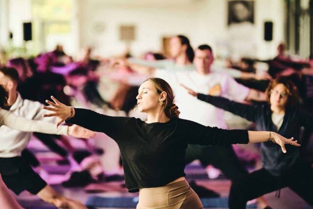 Kobieta ćwicząca jogę w tle inni ludzie