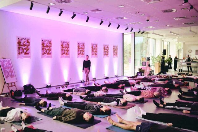 grupa ludzi ćwiczy jogę w dużej otwartej przestrzeni