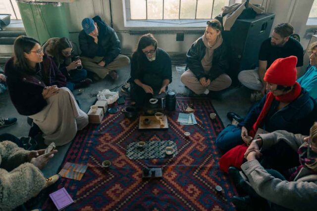 Widok na grupę ludzi siedzącyhc na dywanie