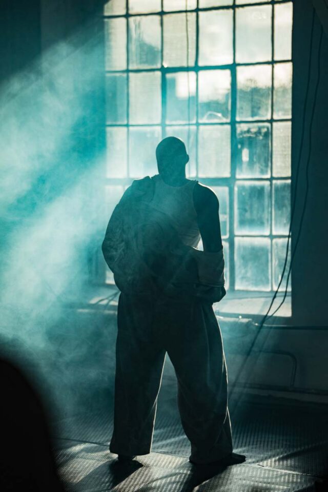 Mężczyzna stoi tyłem na tle okna fabrycznego