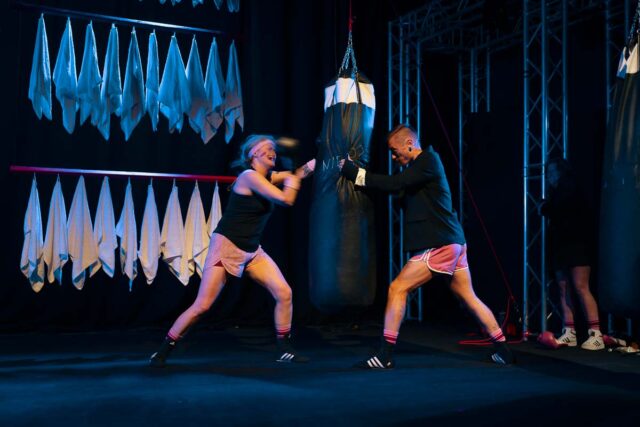 Kobieta i mężczyzna w sportowych strojach uderzają w worek treningowy