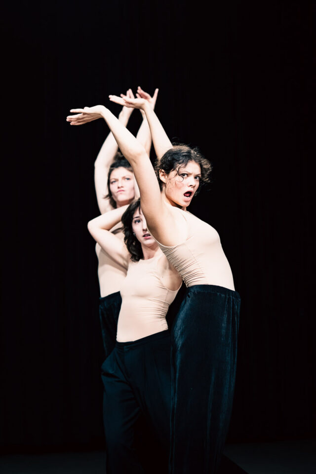 Trzy młode kobiety w cielistych topach z rękoma do góry