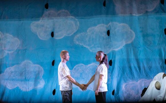 Dwie osoby w białych T-shirtach na tle niebieskiej tkaniny z namalowanymi chmurkami