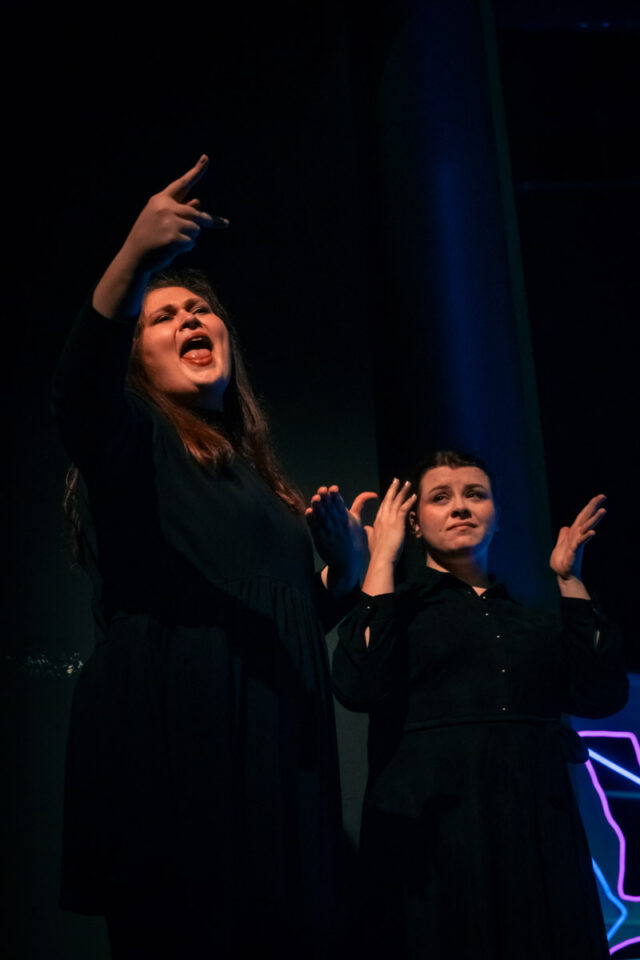 dwie ubrane na czarno młode kobiety w trakcie tłumaczenia na PJM